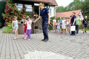 Policjantka zespołu ds. nieletnich prowadzi dziewczynkę, która pokonuje tor przeszkód w alkogoglach