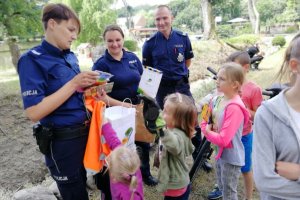 Dzieci odbierają drobne nagrody, odblaski i słodkości od policjantek