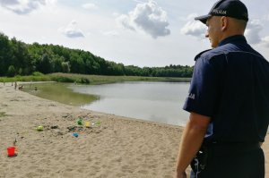 Policjant sprawdza bezpieczeństwo bawiących się na linii brzegowej dzieci