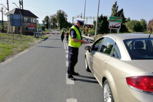 Policjant wyjaśnia kierowcy zasady obowiązujące w chwili zamykania zapór przejazdu kolejowego