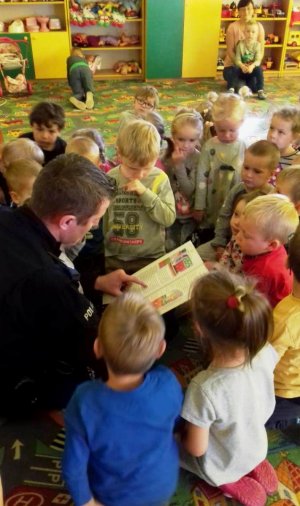 Przedszkolaki wysłuchują rad policjanta podczas czytania bajki