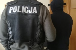 Policjant prowadzi zatrzymanego mężczyznę