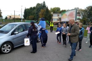 Policjanci wspólnie z Wójtem Gminy Drzycim wręczają upominek kierowcy