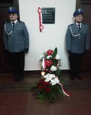 Policjanci stojący na baczność przy tablicy pamiątkowej