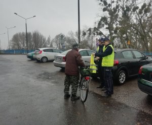 policjanci wręczający kamizelkę odblaskową