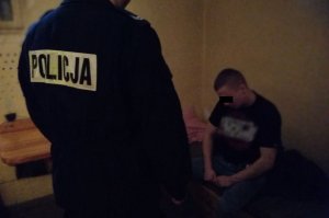 policjant stoi przy zatrzymanym mężczyźnie