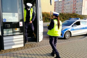 Policjant wychodzi z autobusu, policjantka kontroluje dokumenty