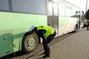 Funkcjonariusz sprawdza opony autobusu