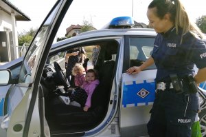 Policjantka prezentuje radiowóz predszkolakom