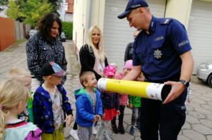 Chłopiec uśmiecha się do policjanta trzymającego profilaktyczną tubę