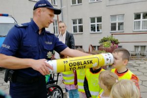 Policjant pokazuje działanie odblasków za pomocą tuby