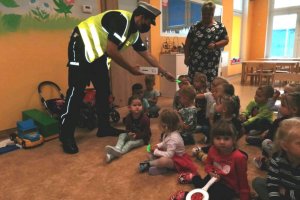 Policjant rozdaje odblaskowe zawieszki dzieciom