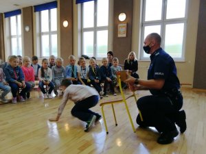 Policjant podczas eksperymentu zrzuca chłopca z krzesła