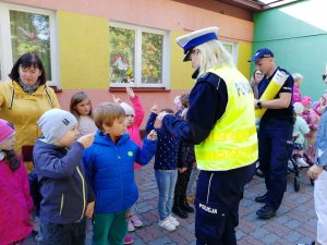 Policjantka rozdaje odblaski przedszkolakom