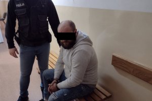 Zatrzymany listem gończym mężczyzna pilnowany przez policjanta