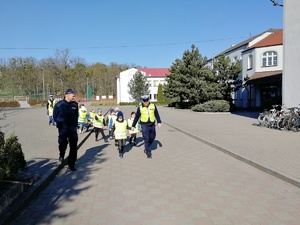 Policjant drogówki prowadzi dzieci na przejście