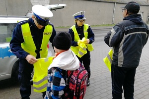 Policjant drogówki prezentuje kamizelkę chłopcu