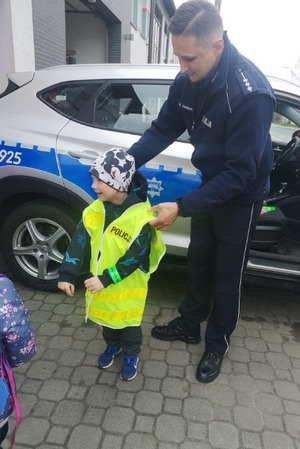 Policjant demonstruje słuchaczom kamizelkę odblaskową