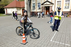 Uczestniczka jedzie na rowerze a policjant kontroluje jazdę