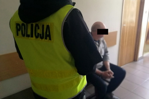 Policjant pilnuje zatrzymanego do sprawy wypadku mężczyznę