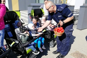 Policjant wręcza dzieciom piłeczki