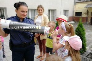 Policjantka prezentuje działanie odblasków za pomocą tuby