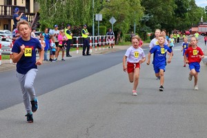 Dzieci biegną ulicą, policjanci kierują ruchem