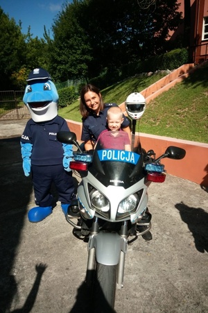 Policjantka siedzi z dzieckiem na służbowym motocyklu