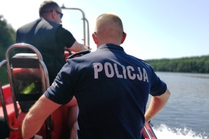 Policjant i strażak płyną łodzią służbową