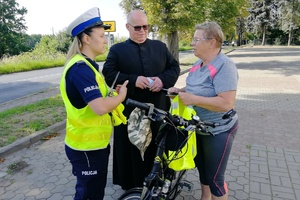 Policjantka i Kapelan Policji rozmawiają z rowerzystką