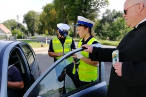 Mundurowi wraz z Kapelanem rozmawiają z zatrzymanym do kontroli kierowcą