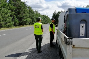 Policjant i strażnik leśny kontrolują kierowcę samochodu ciężarowego