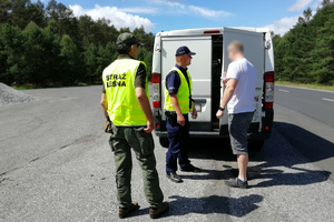 Policjant tłumaczy kierowcy zasady zabezpieczania przewożonego ładunku