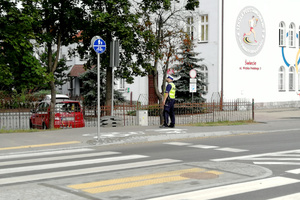 Mundurowy spogląda, czy postawiony przy szkole znak jest dostatecznie widoczny