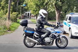 Policjant na motocyklu przejeżdża obok radiowozu