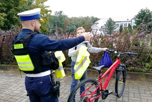 Funkcjonariusz przekazuje kamizelkę rowerzyście