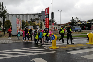 Policjanci drogówki przeprowadzają uczniów przez jezdnię