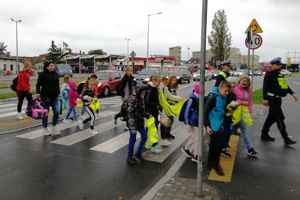 Dzieci przechodzą z policjantami przez przejście w rejonie szkoły