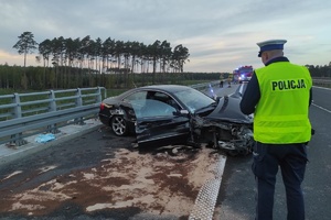 Policjant prowadzi oględziny miejsca wypadku drogowego