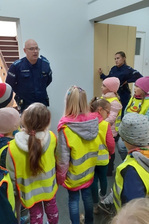 Policjant prowadzi prelekcję z dziećmi na terenie komisariatu