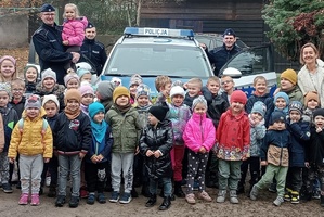 Pamiątkowe zdjęcie policjantów i przedszkolaków na tle radiowozu