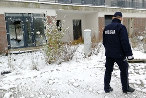 Policjant idzie wzdłuż opuszczonego budynku