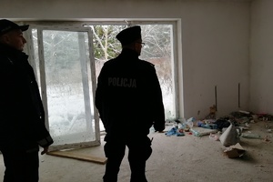Policjanci w pomieszczeniu opuszczonego budynku kontrolują przebywających bezdomnych