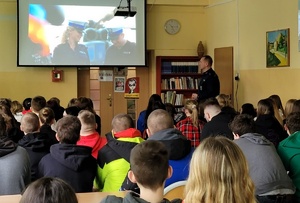 Policjant prezentuje film dotyczący pracy ruchu drogowego