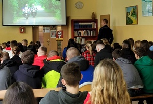 Policjant wyjaśnia uczniom specyfikę pracy policjantów na różnych stanowiskach