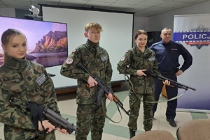 Uczniowie trzymając długą broń pozują do zdjęcia
