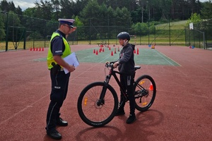 Policjant tłumaczy rowerzyście zasady egzaminu