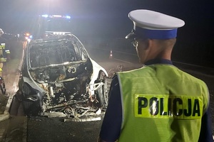 Policjant zabezpiecza miejsce spalonego pojazdu