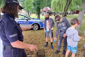 Policjantka prowadzi konkurencję rzutu piłeczka do pojemnika