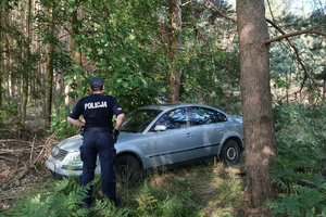 Policjant prowadzi oględziny porzuconego samochodu